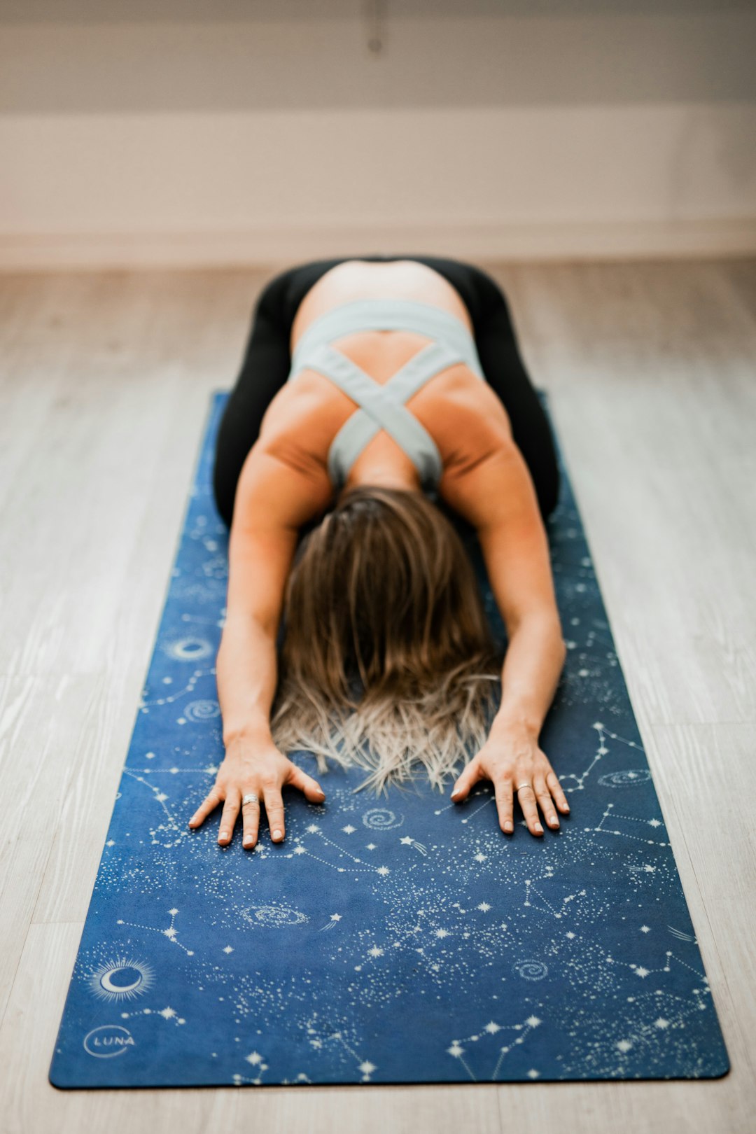 about-us-01 Girl on celestial, space, astro yoga mat, childs pose